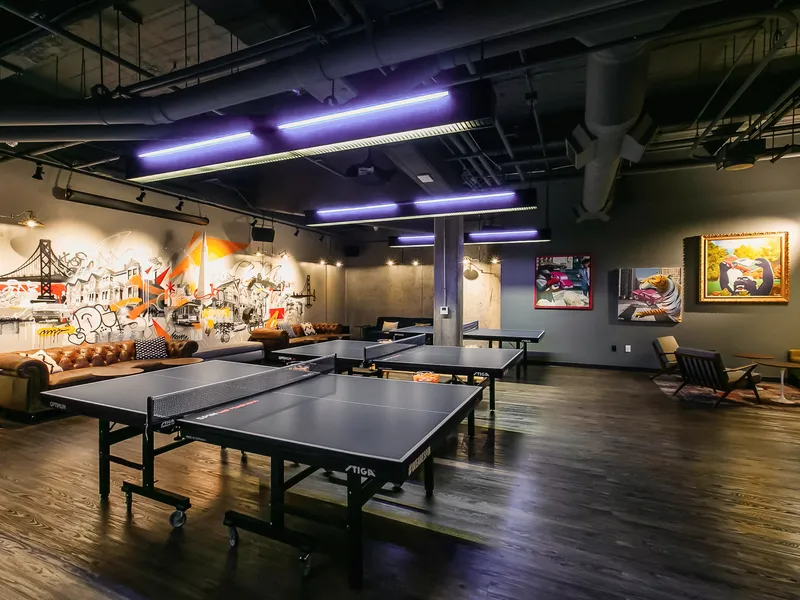Ping pong tables beside lounge seating and wall art in the main hall at SPIN San Francisco