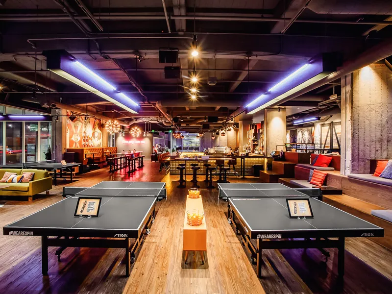 A row of ping pong tables stretching past the bar and lounge at SPIN San Francisco