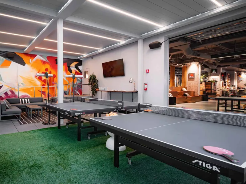 The covered patio at SPIN San Francisco with astroturf, a mural, and a ping pong table